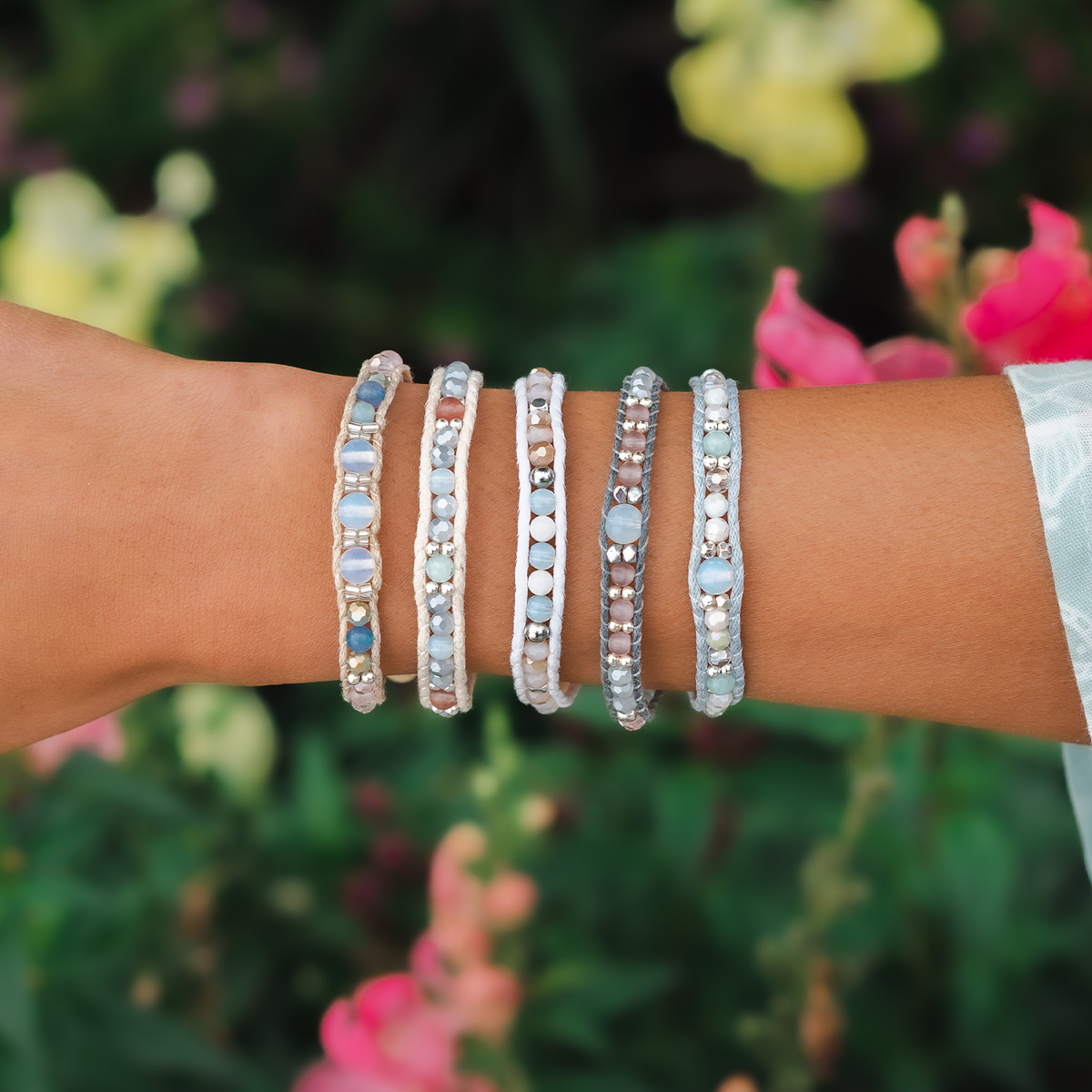 Forearm adorned with a stack of Moonbeam bracelets in pale beads outdoors