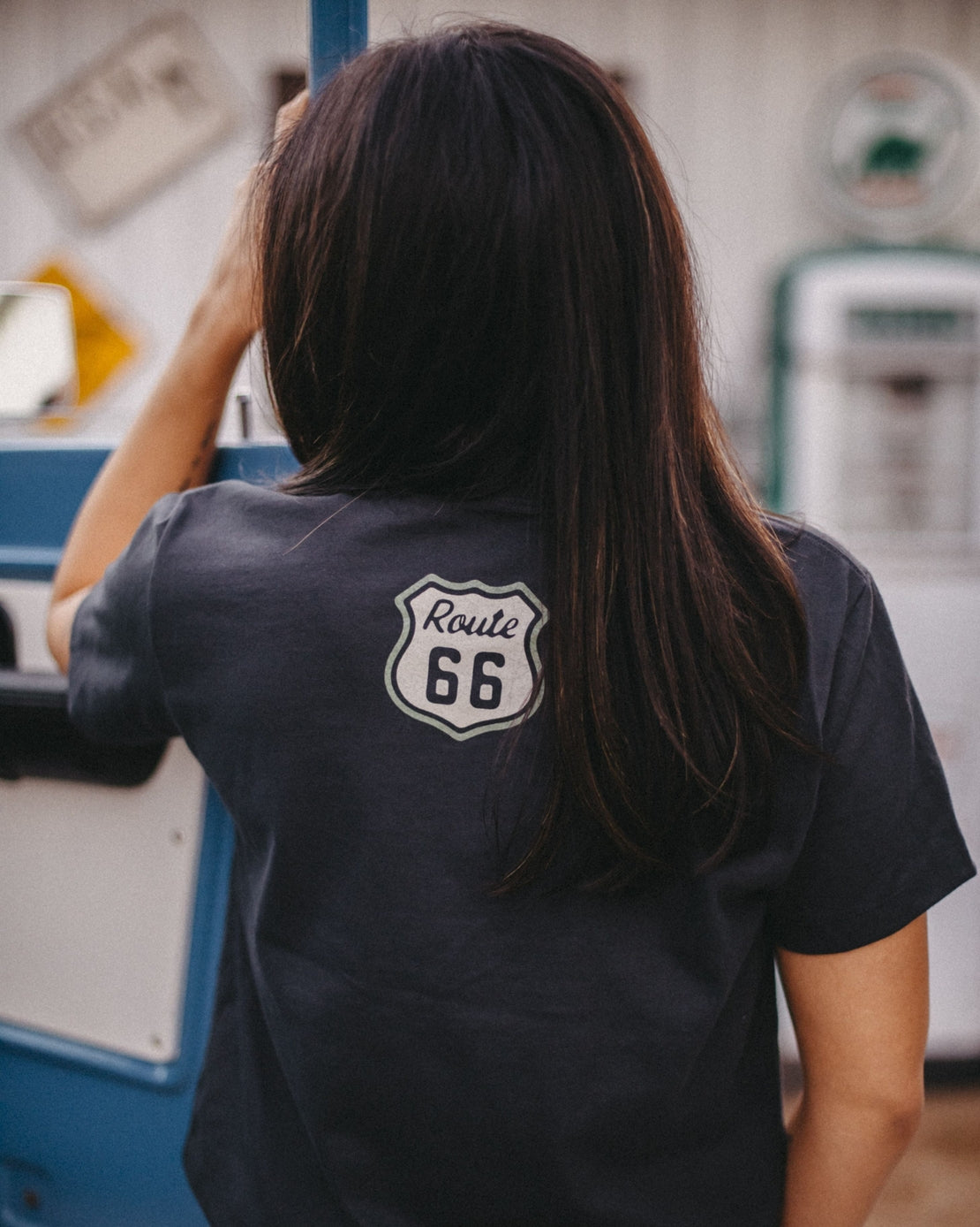 Back view of a woman wearing a Route 66 tee with a shield graphic on the back.