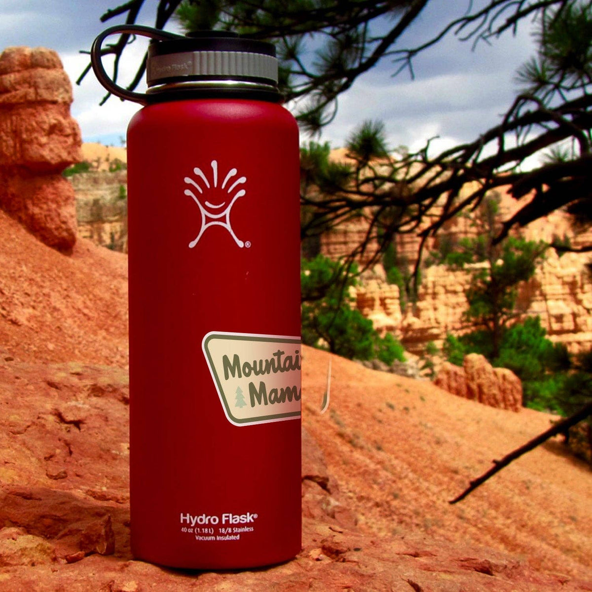 Mountain Mama sticker on a red Hydro Flask set against a desert canyon landscape