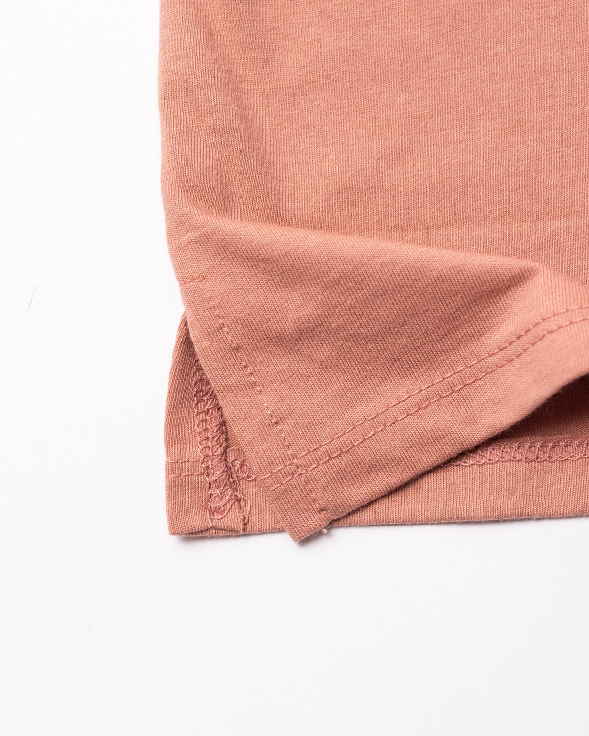 Close up of coral pink tank fabric edge and seam with folded hem