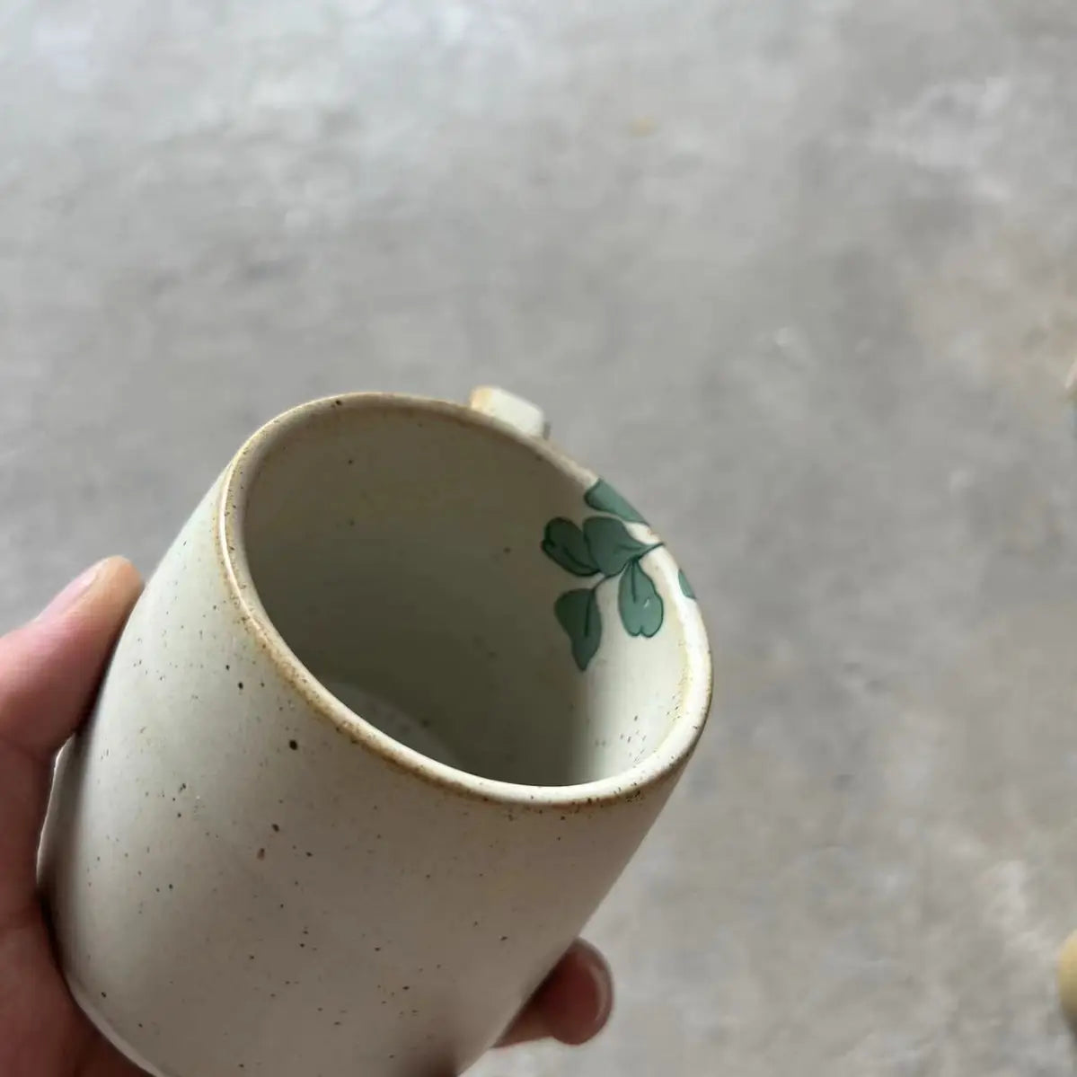 Top view of cream speckled sunflower mug with green leaf accent near the rim
