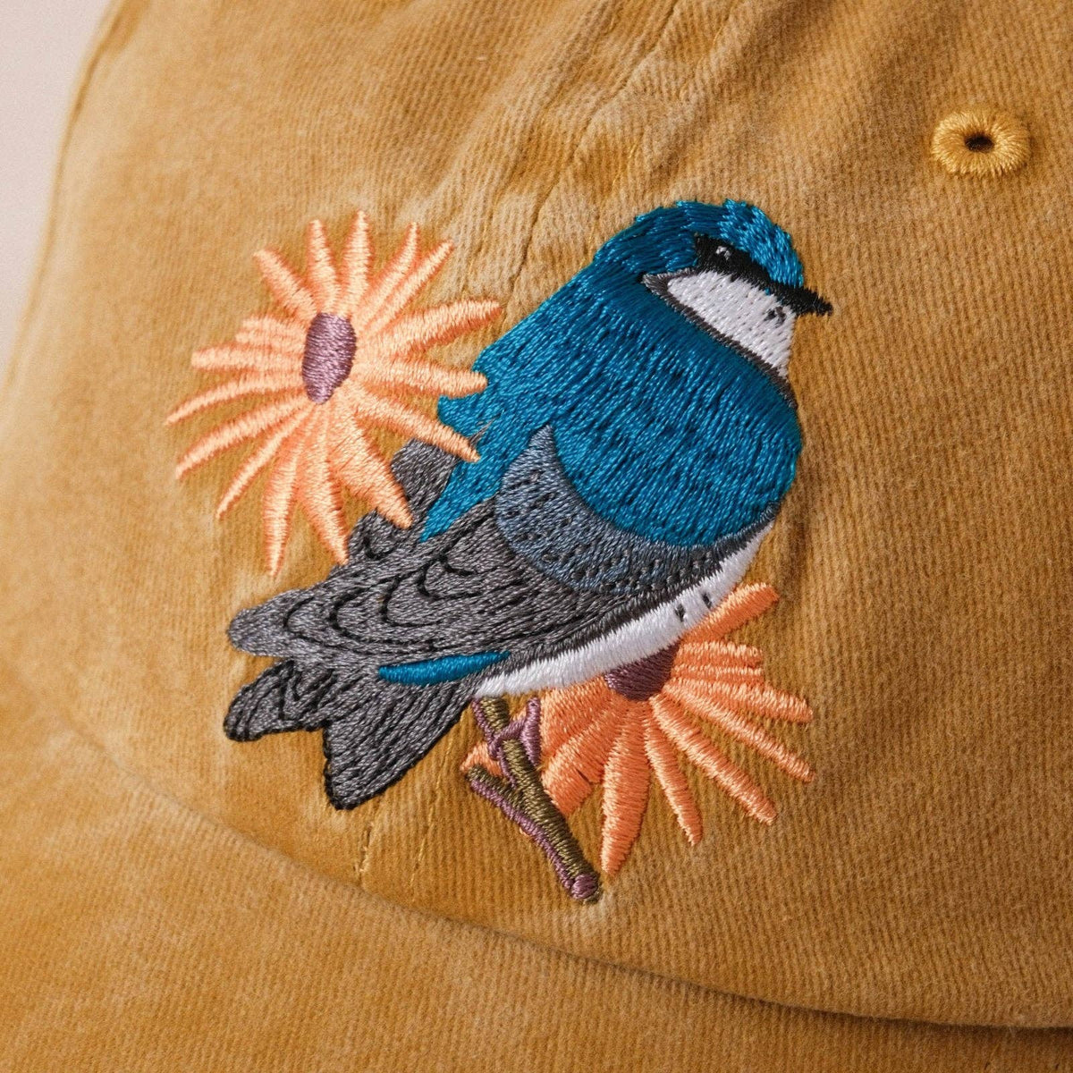 Embroidered blue tree swallow with peach flowers on a tan washed dad hat