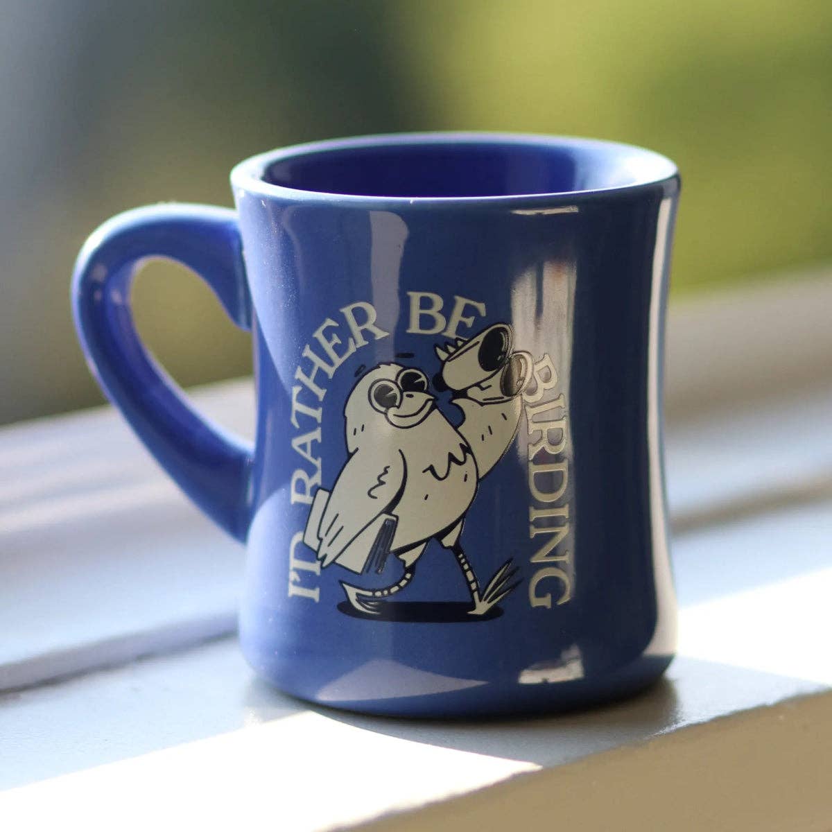 Blue ceramic mug with a white bird illustration and the phrase I'd Rather Be Birding.