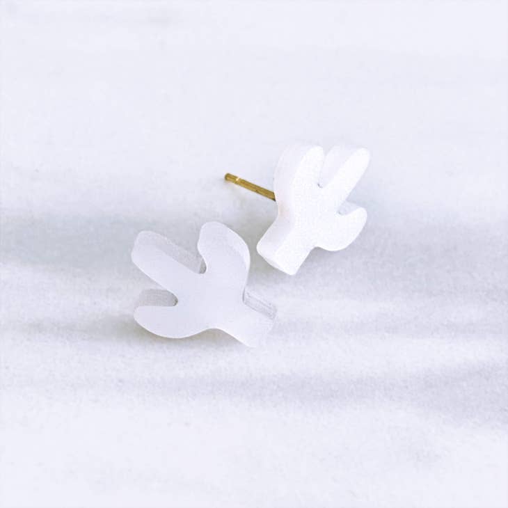 White acrylic cactus stud earrings with gold posts on a soft light background
