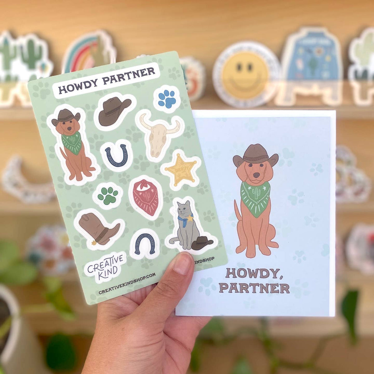 Sticker sheet with cowboy-themed stickers and a matching card held by a hand.