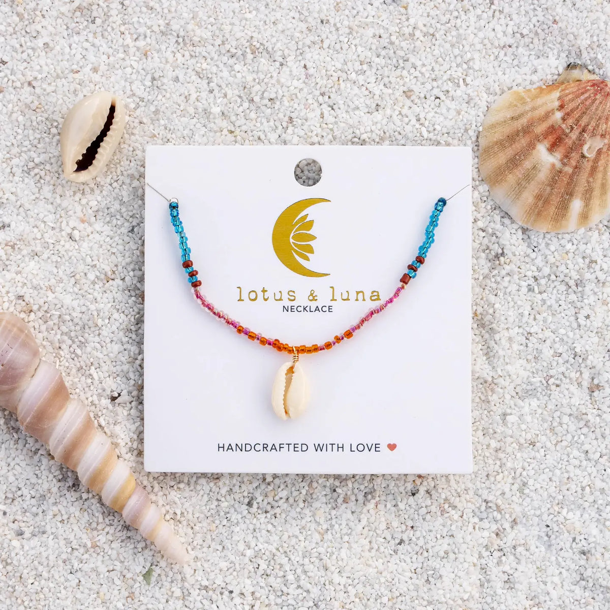 Mermaid's Tale seed bead necklace displayed on a Lotus & Luna card on sandy beach