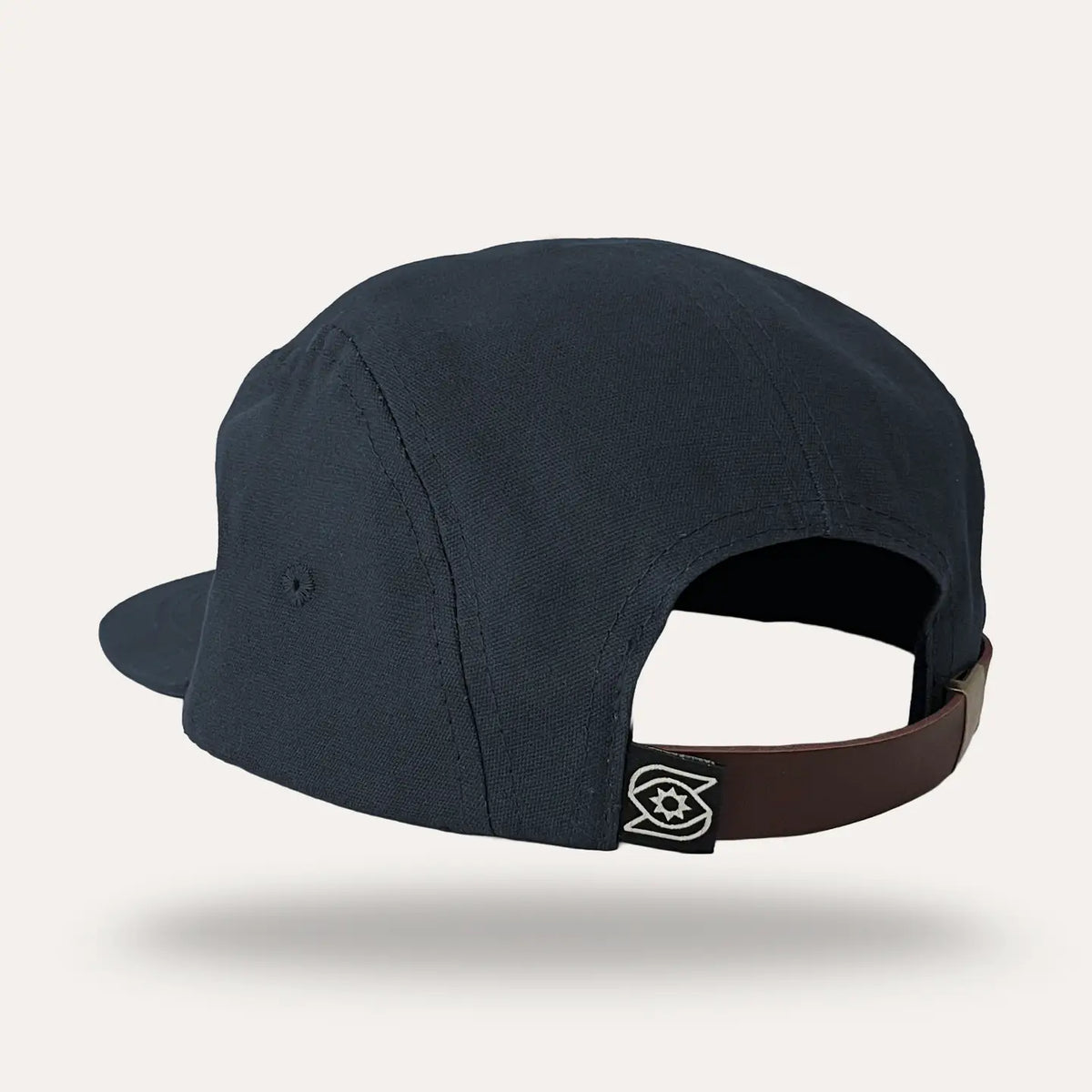 Back view of the midnight blue hat with a brown adjustable strap and a small brand patch