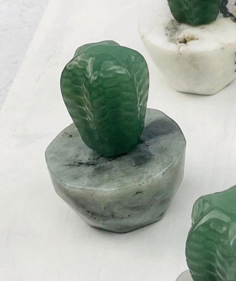 Green crystal cactus sculpture atop a gray hexagonal base.