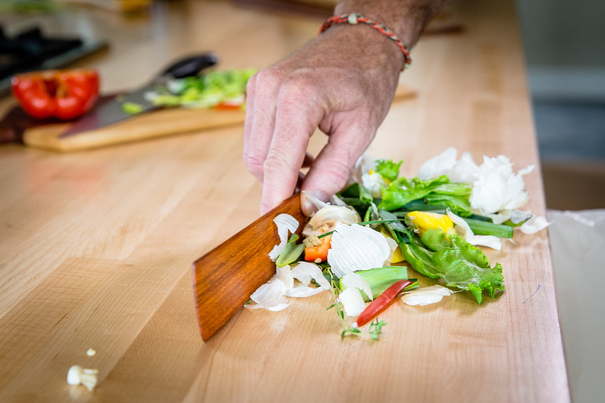 Assorted chopped vegetables on a cutting board with a wooden spatula ready to stir