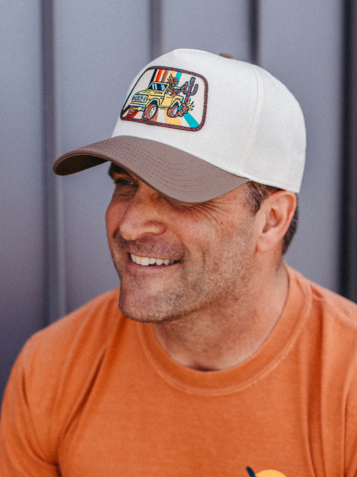 Bronco curved brim hat with white crown and tan brim featuring a colorful patch of a yellow jeep in a desert scene.