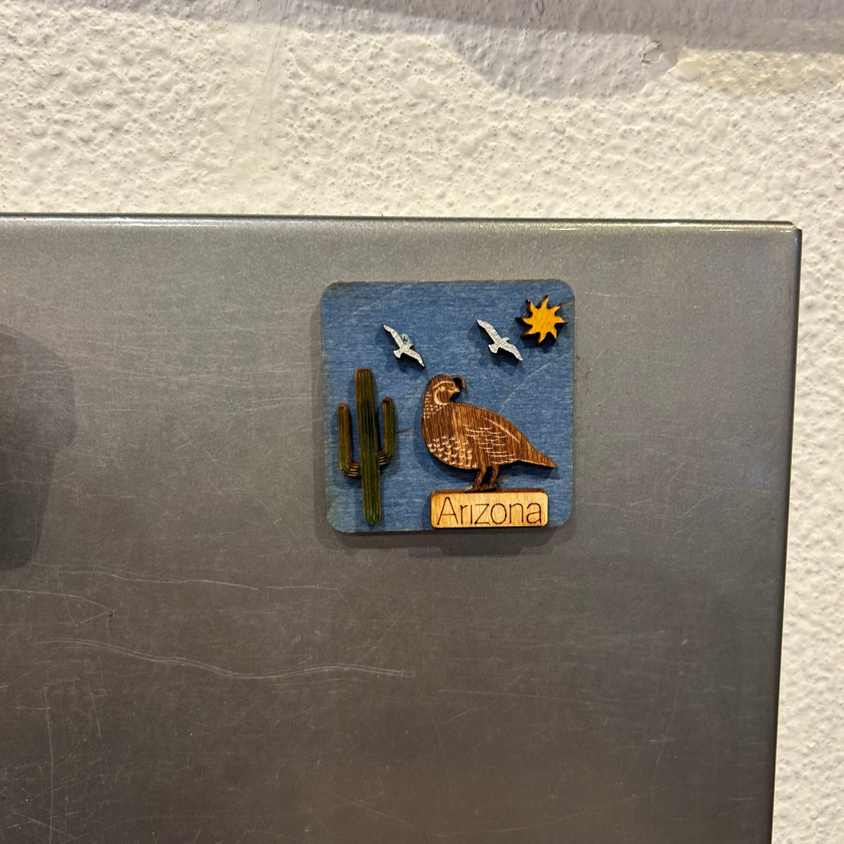 Tiny Arizona wooden magnet mounted on blue background showing desert cactus motif