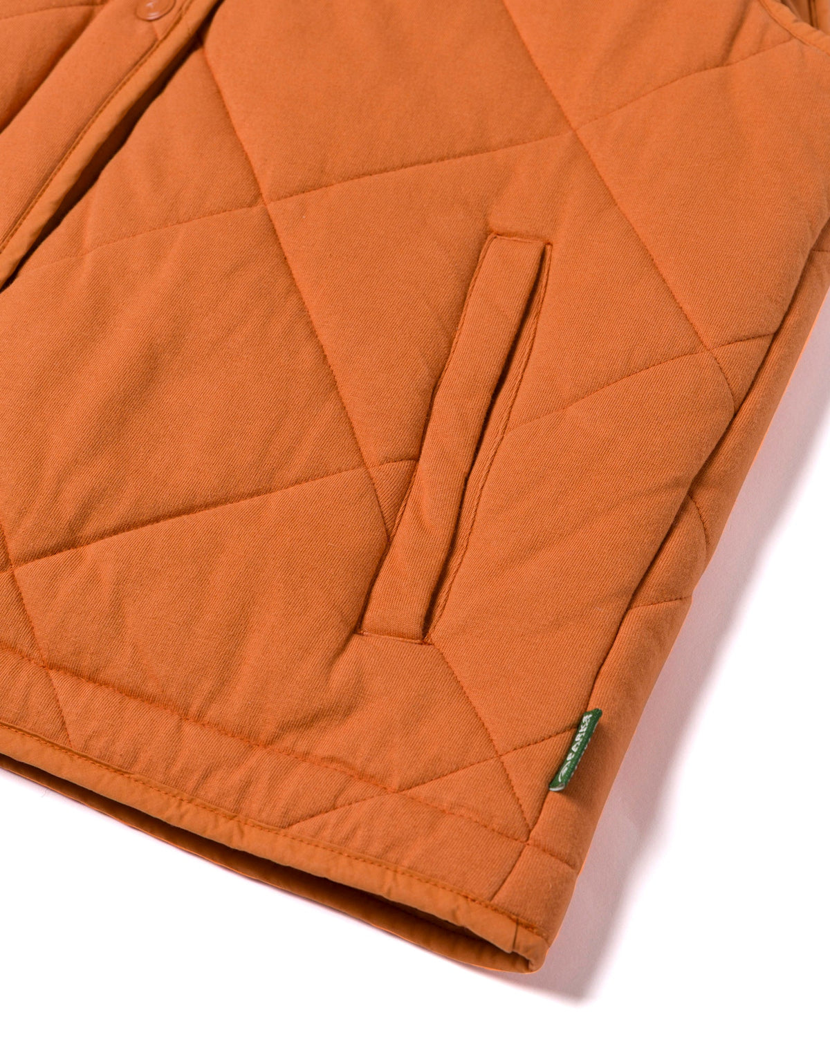 Close up of orange quilted puffer vest with front pocket and button detail