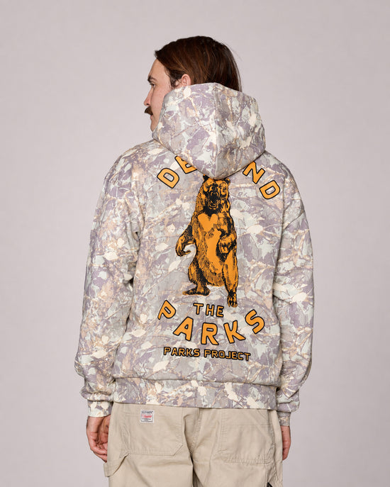 Back view of Defend the Parks Bear Hoodie with a large orange bear graphic and arched orange text on gray camouflage