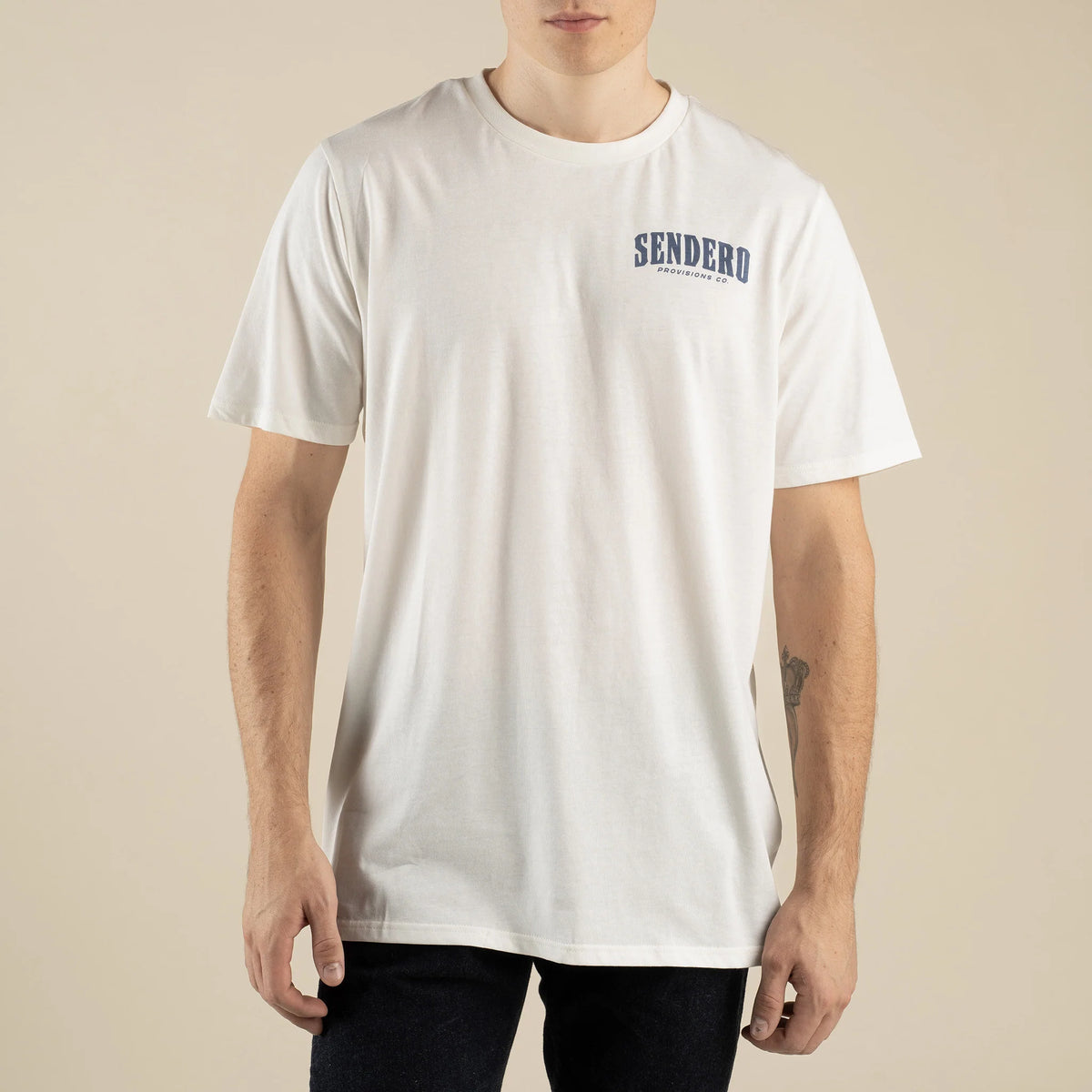 Man wearing white We Needed This Rain Tee with curved Sendero Provisions Co logo on the chest