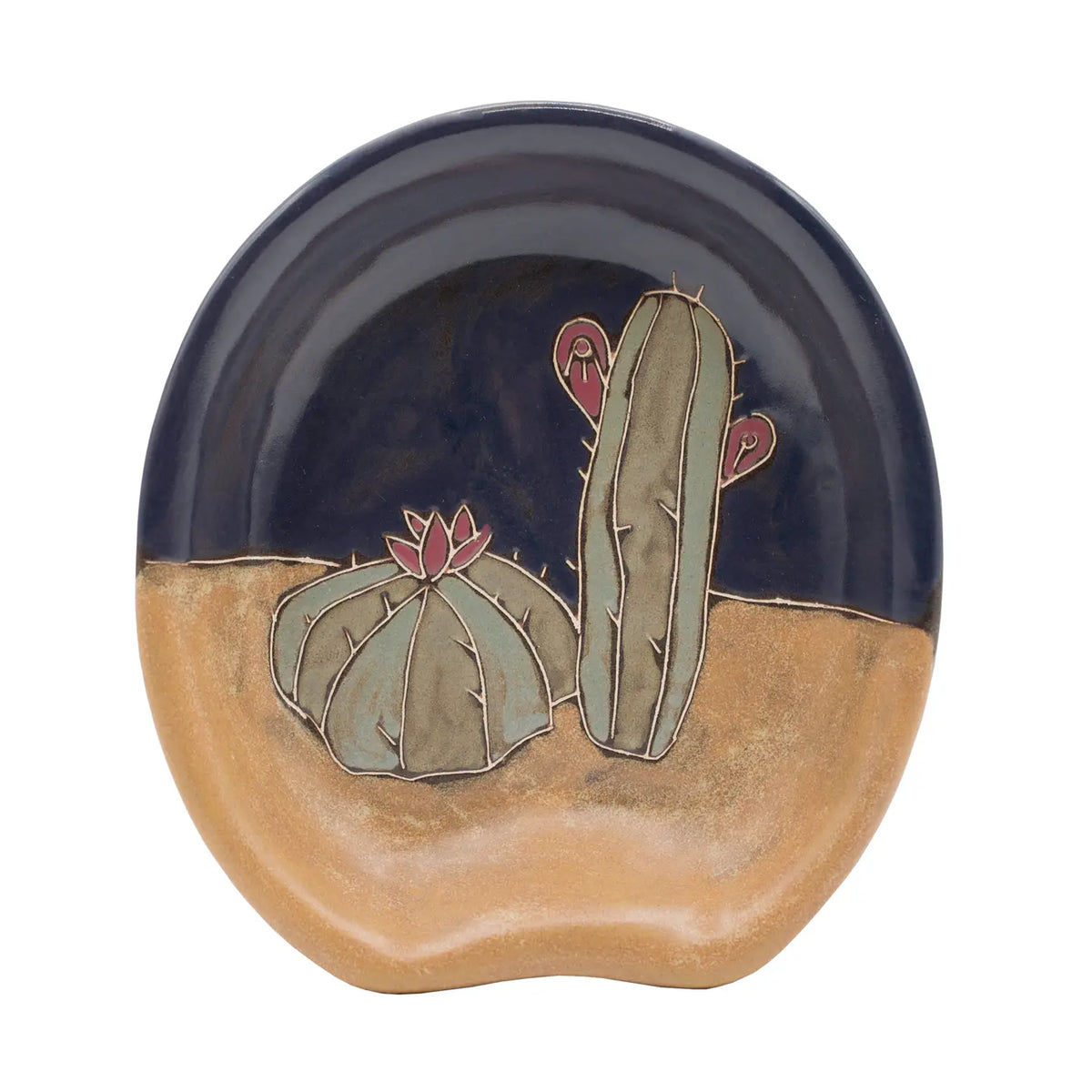 Desert motif spoon rest with pale green cacti against tan sand and a dark blue sky.