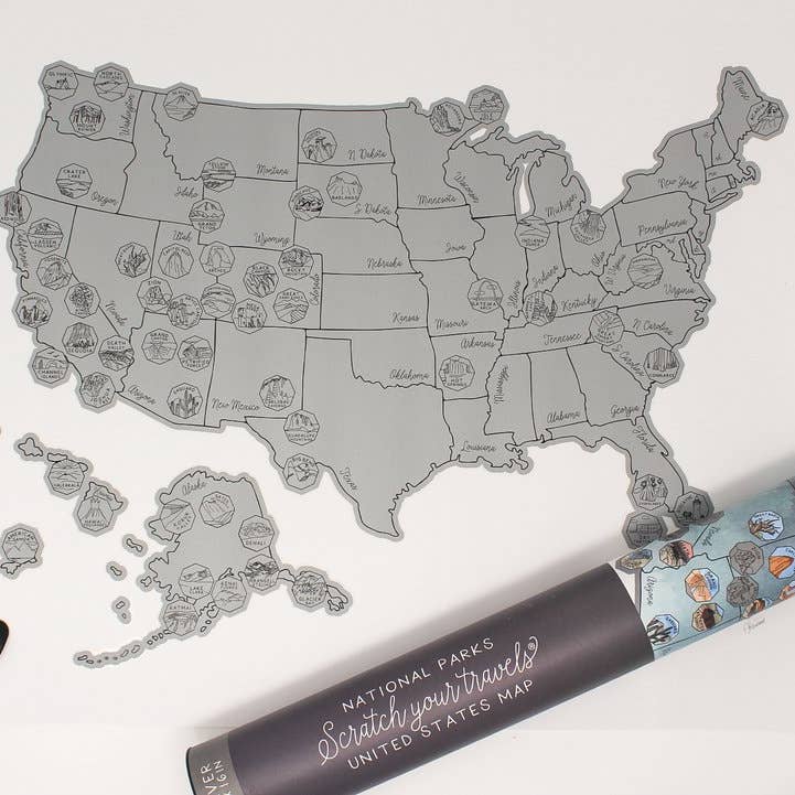 Overview of the 63 US National Parks scratch-off map laid flat with numerous state stamps across the United States