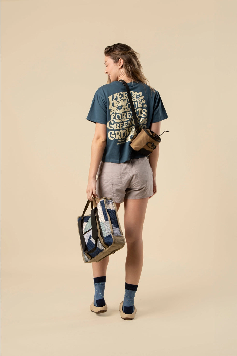 Back view of model wearing navy blue boxy crop tee featuring a large cream graphic and floral design.