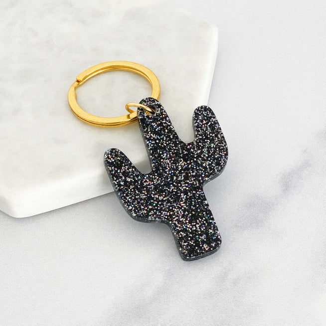 Acrylic cactus shaped keyring with black glitter attached to a gold ring