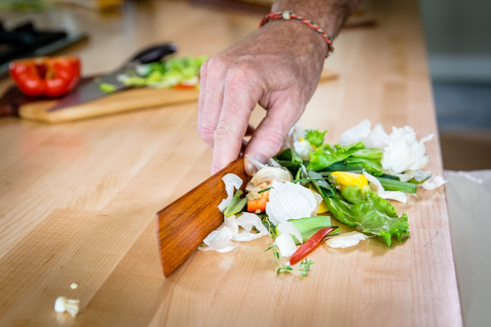 Hand chopping mixed vegetables for salad on a wooden kitchen counter