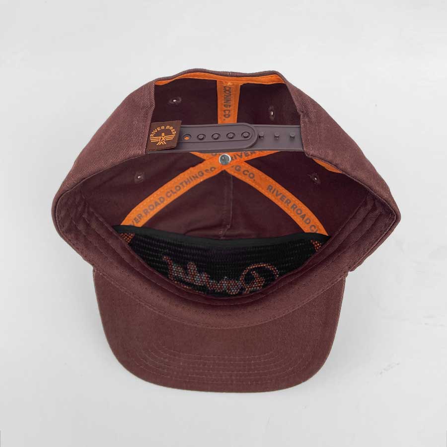 Back view of a brown Rowdy flatbrim hat showing orange interior lining and an adjustable strap.