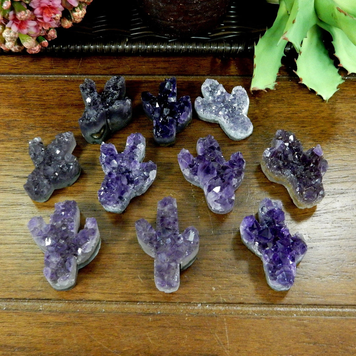 Group of raw carved amethyst cactus clusters arranged on a wooden surface