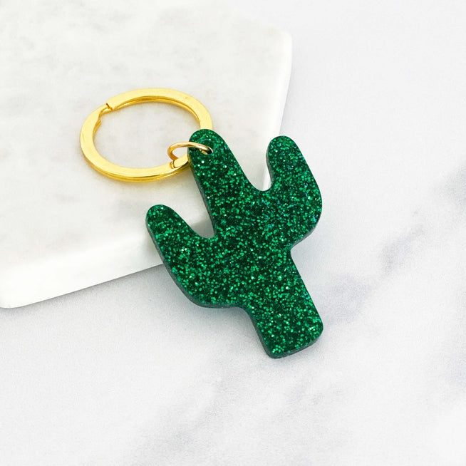 A green glitter acrylic cactus keyring attached to a gold ring