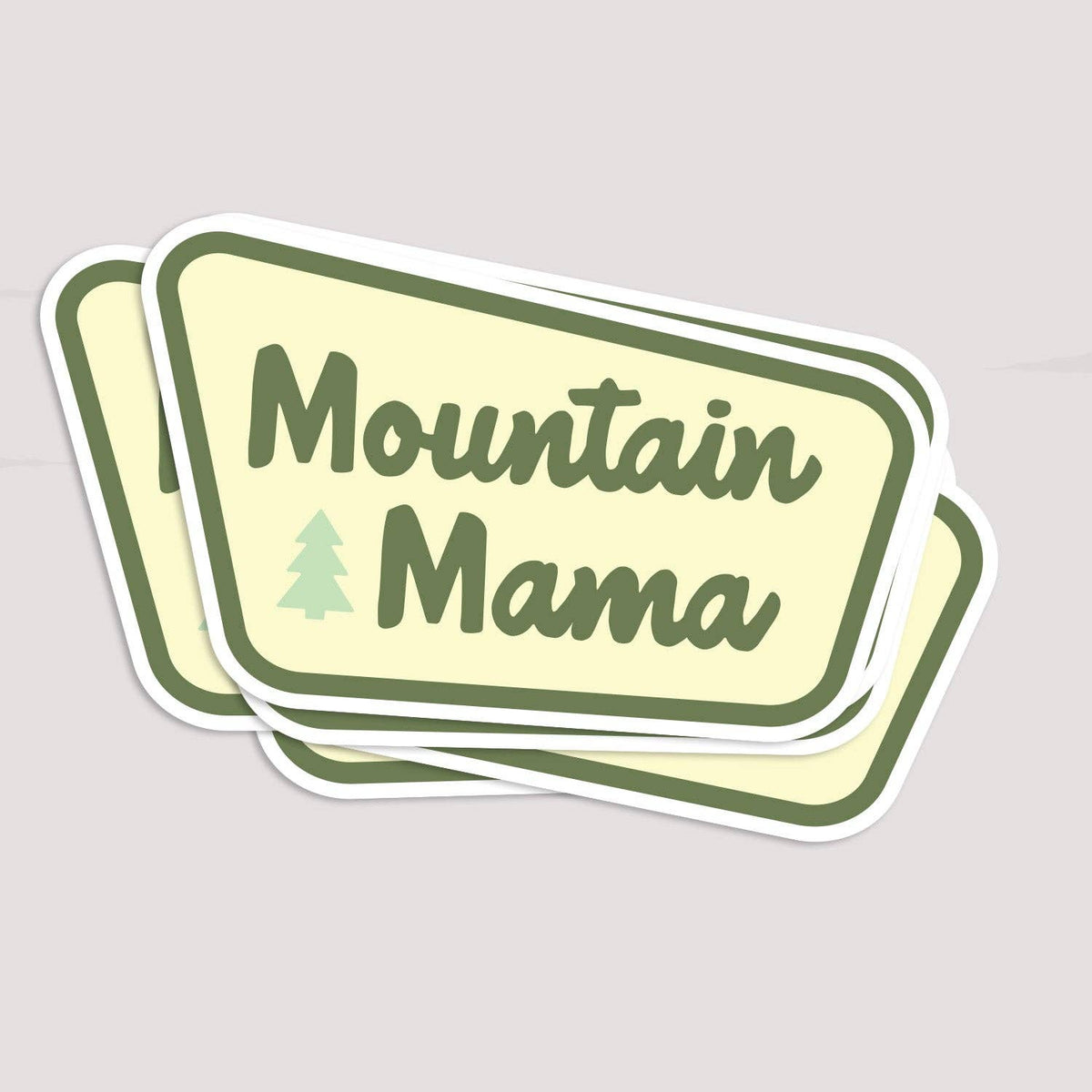 Stacked Mountain Mama sticker with pale yellow background and green border and a small pine tree icon
