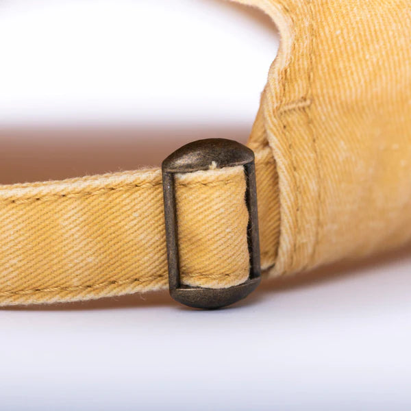 Close up of the back strap adjuster on a mustard Sol Mate dad hat