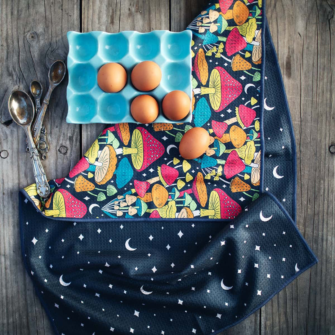 Eggs on a blue egg carton atop a rustic wooden surface with the Midnight Mushroom towel visible nearby