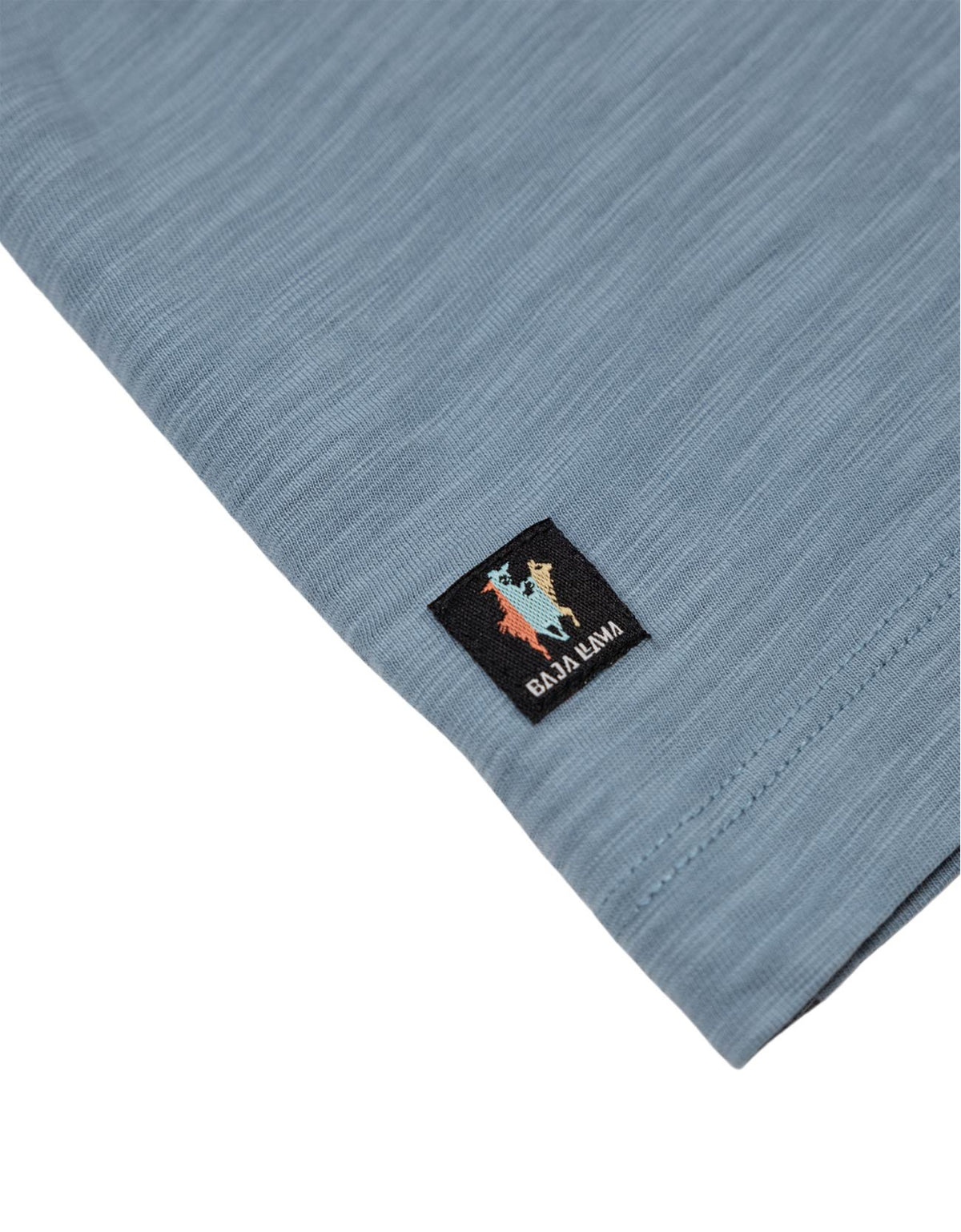 Close up of the Sun Dream tee fabric showing the sleeve pocket and Baja Llama logo patch.