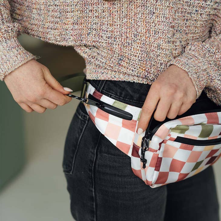 Hands zipping a pastel checkered Everyday Fanny Pack at the waist