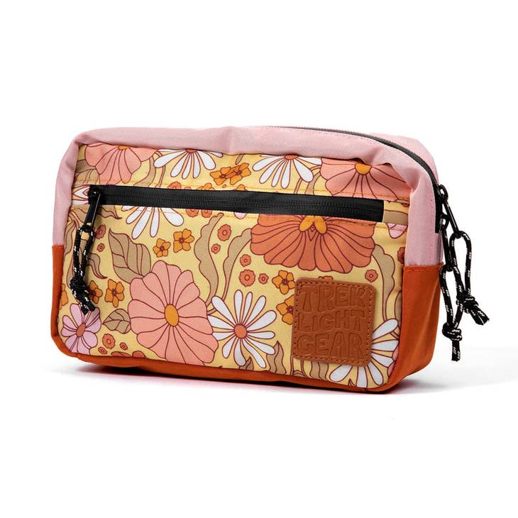 Pink floral print fanny pack with black zip pocket and brown Trek Light Gear patch.