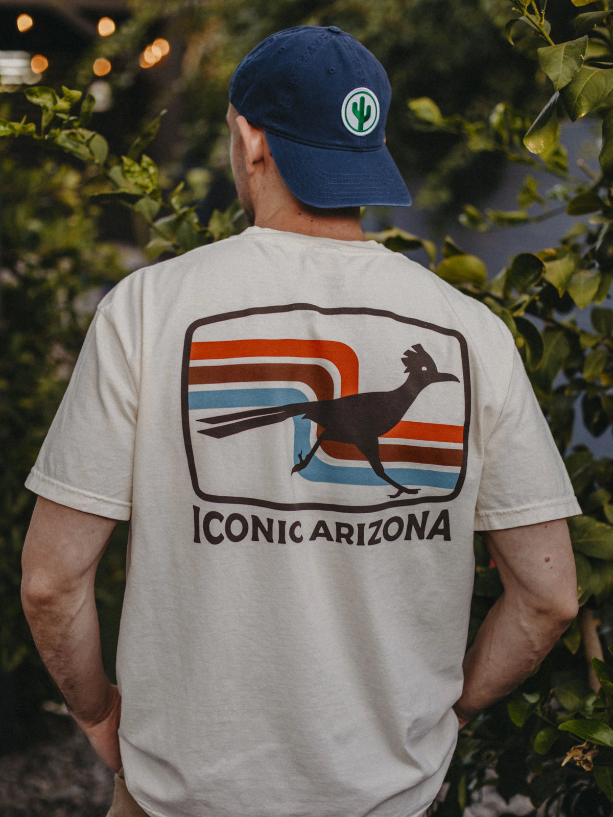 Back view of a person wearing a cream 70s retro roadrunner tee with a bold graphic and Iconic Arizona text