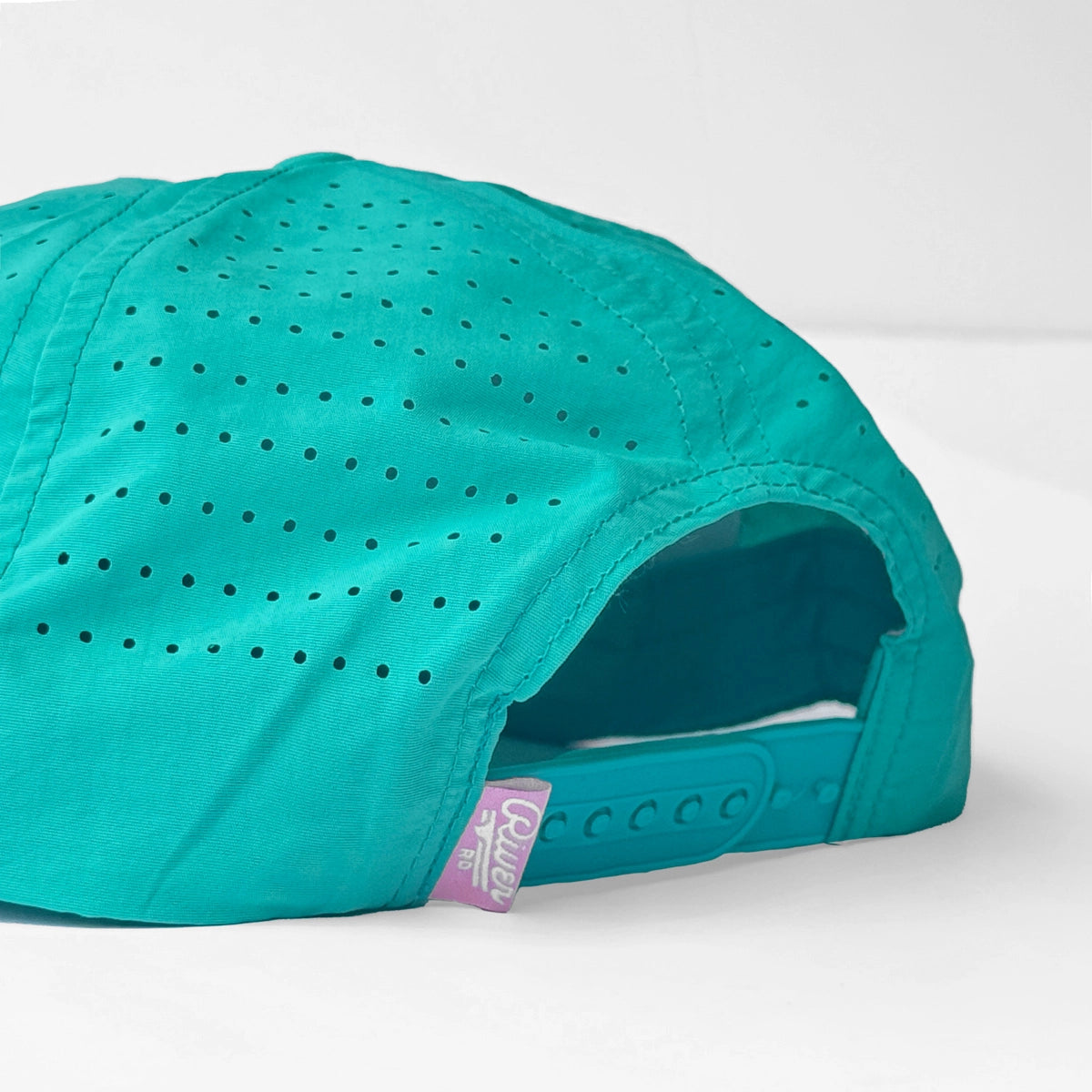 Back view of teal Good Times Float Club flatbrim hat with perforated crown and adjustable teal strap plus pink River Road Clothing Co tag