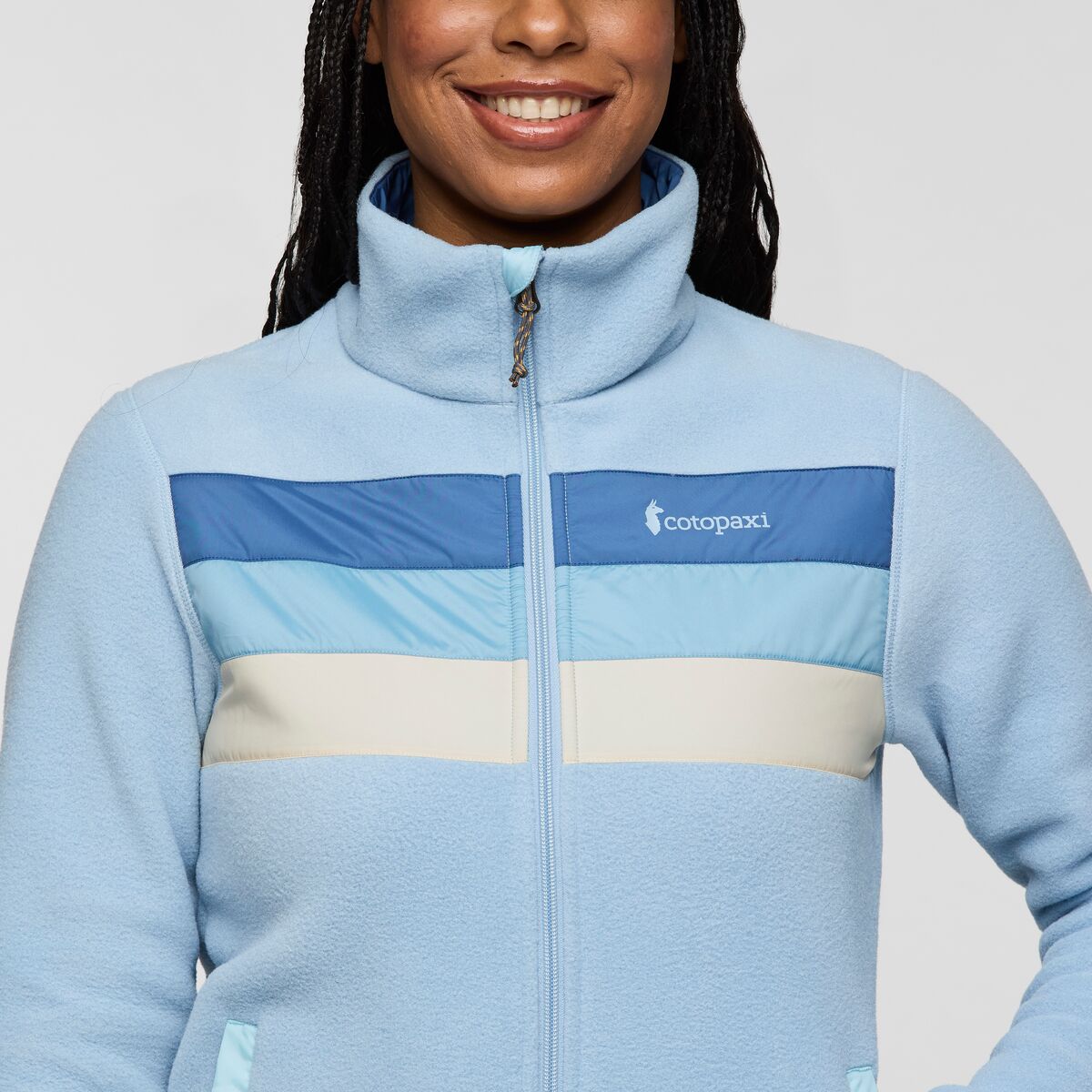 Close up of Cotopaxi Teca fleece full zip jacket showing blue color block panels and the Cotopaxi logo on the chest
