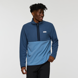 Male model wearing the Cotopaxi Amado Fleece Pullover in a two tone blue design with chest patch