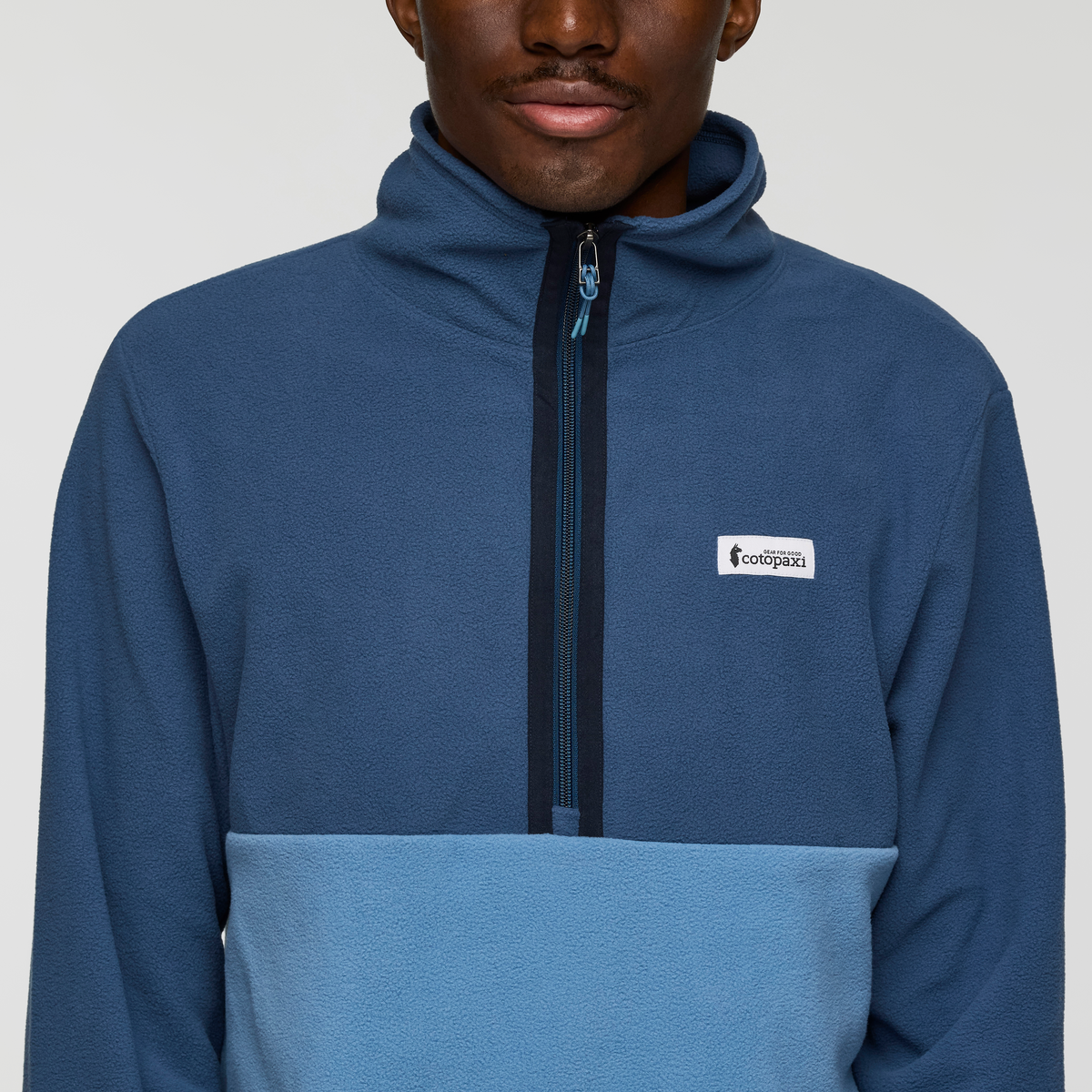 Front view of Cotopaxi Amado fleece pullover in blue with zip front and small logo patch on the left chest