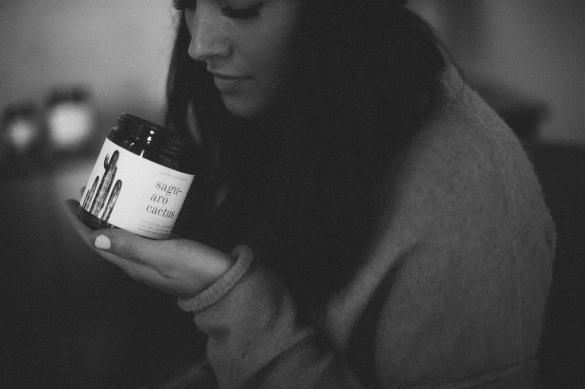 Person holding a Saguaro Cactus candle jar in a moody black and white photograph
