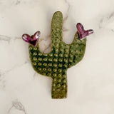 Green saguaro cactus ceramic magnet with purple heart tips.