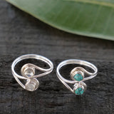 Two silver wrap rings each with a round cabochon stone turquoise on one and a pale stone on the other