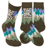 Socks with a brown base featuring a colorful pine forest motif and the bold text May the Forest Be With You.