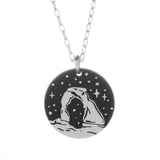 Round silver pendant necklace featuring a Delicate Arch silhouette against a starry night background.