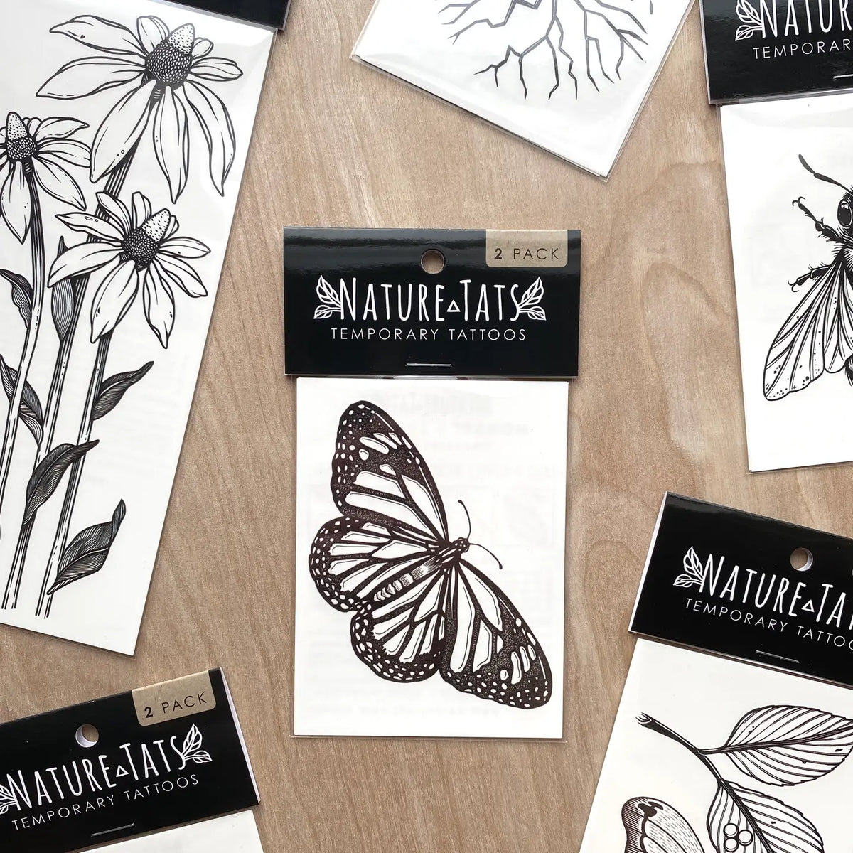 NatureTats two pack butterfly temporary tattoos shown on black packaging with botanical drawings.