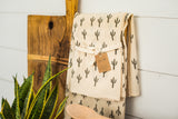 Cotton Saguaro Tea Towel with cactus print hanging on a rustic wooden rack