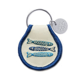 Sardines patch keychain with beige fabric and blue trim, attached to a metal ring.