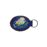 Navy blue oval keychain with orange stitching showing a frog wearing a yellow hat on a green inflatable ring in water