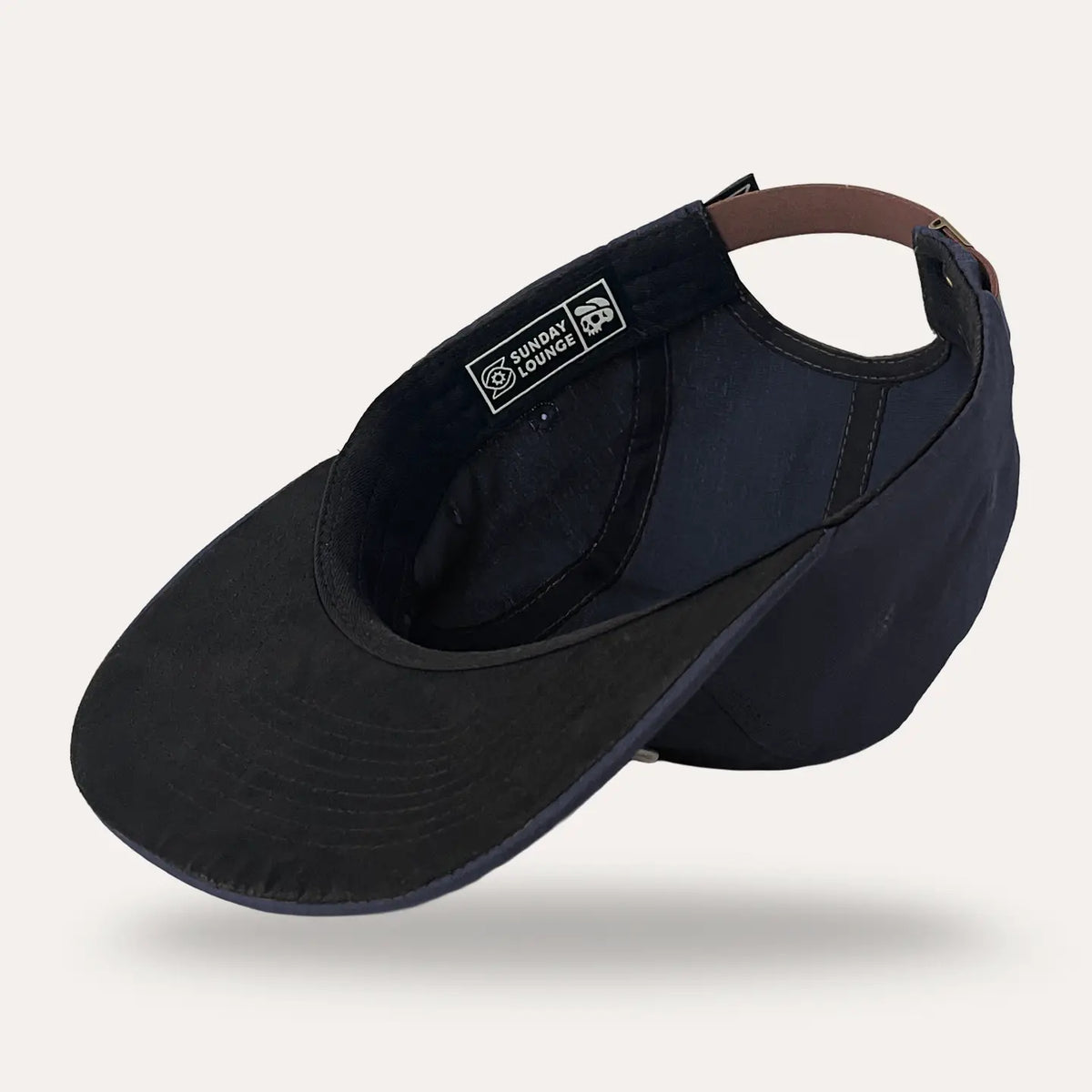 Rear view of the midnight blue cap highlighting the brown strap and back brand patch