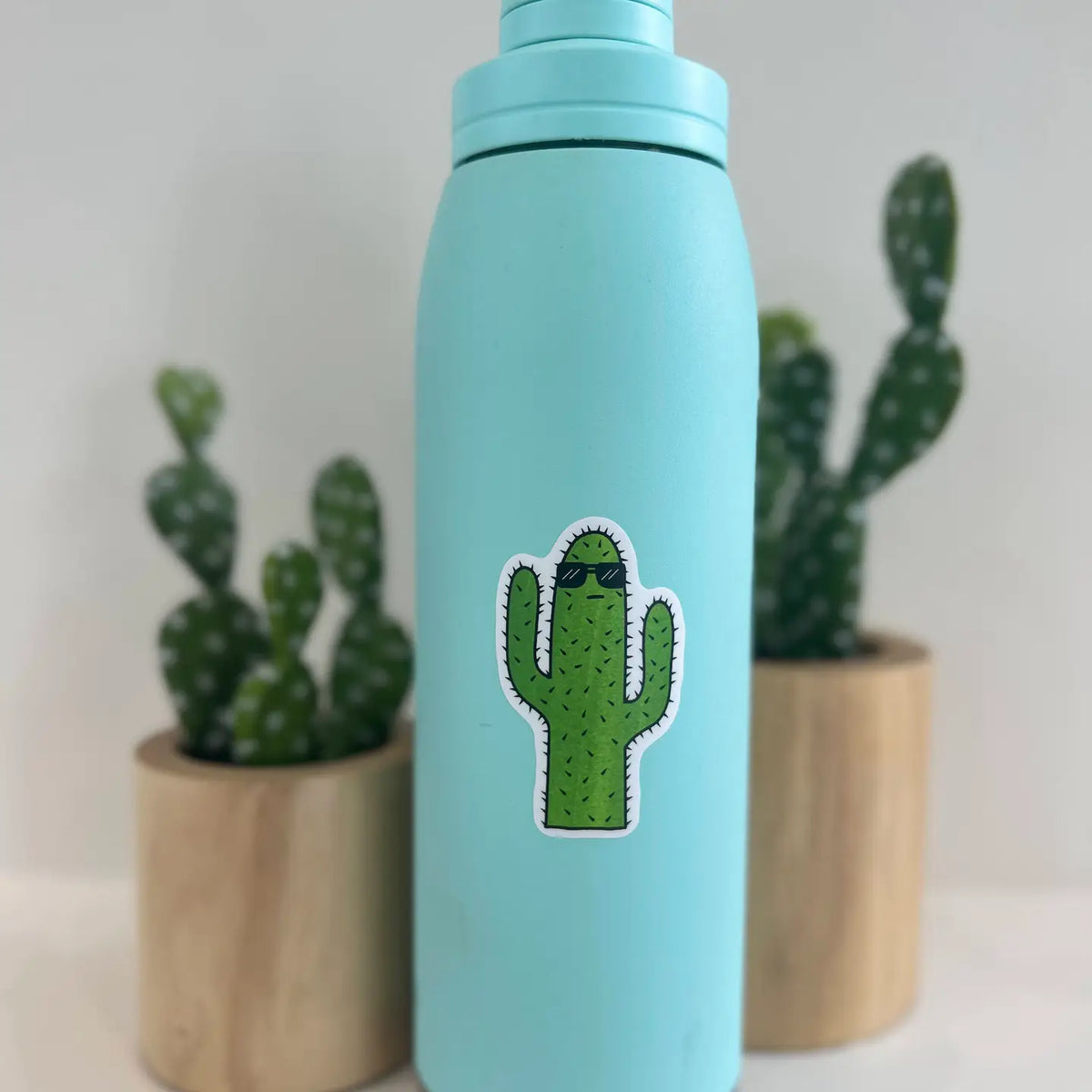 Turquoise water bottle featuring a saguaro cactus sticker wearing sunglasses