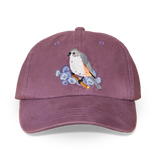 Embroidered tufted titmouse perched on a branch with blue flowers on a purple washed dad hat