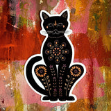 Cat matte vinyl sticker of a black cat with orange floral patterns and a white border against a colorful painterly background